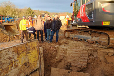 Das Team des Geschäftsbereich Krankenhausneubau und die Mitarbeiter der Baustelle vor den ersten Geländearbeiten. In der Mitte Projektleiter und stellvertretender Bereichsleiter Tom Buge.