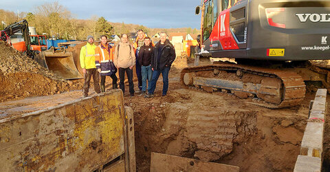 Das Team des Geschäftsbereich Krankenhausneubau und die Mitarbeiter der Baustelle vor den ersten Geländearbeiten. In der Mitte Projektleiter und stellvertretender Bereichsleiter Tom Buge.